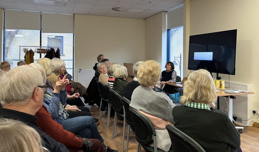 Members of Garden Group 1 sittin in rows listening to a speaker